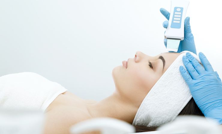 Skin therapist performing a deep cleansing facial with an ultrasonic device