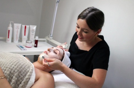 therapist in black shirt performing deep cleansing facial on a woman