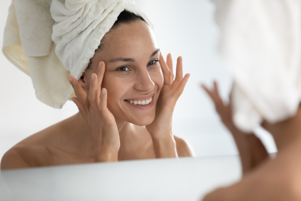 woman with clear skin smiling in the mirror